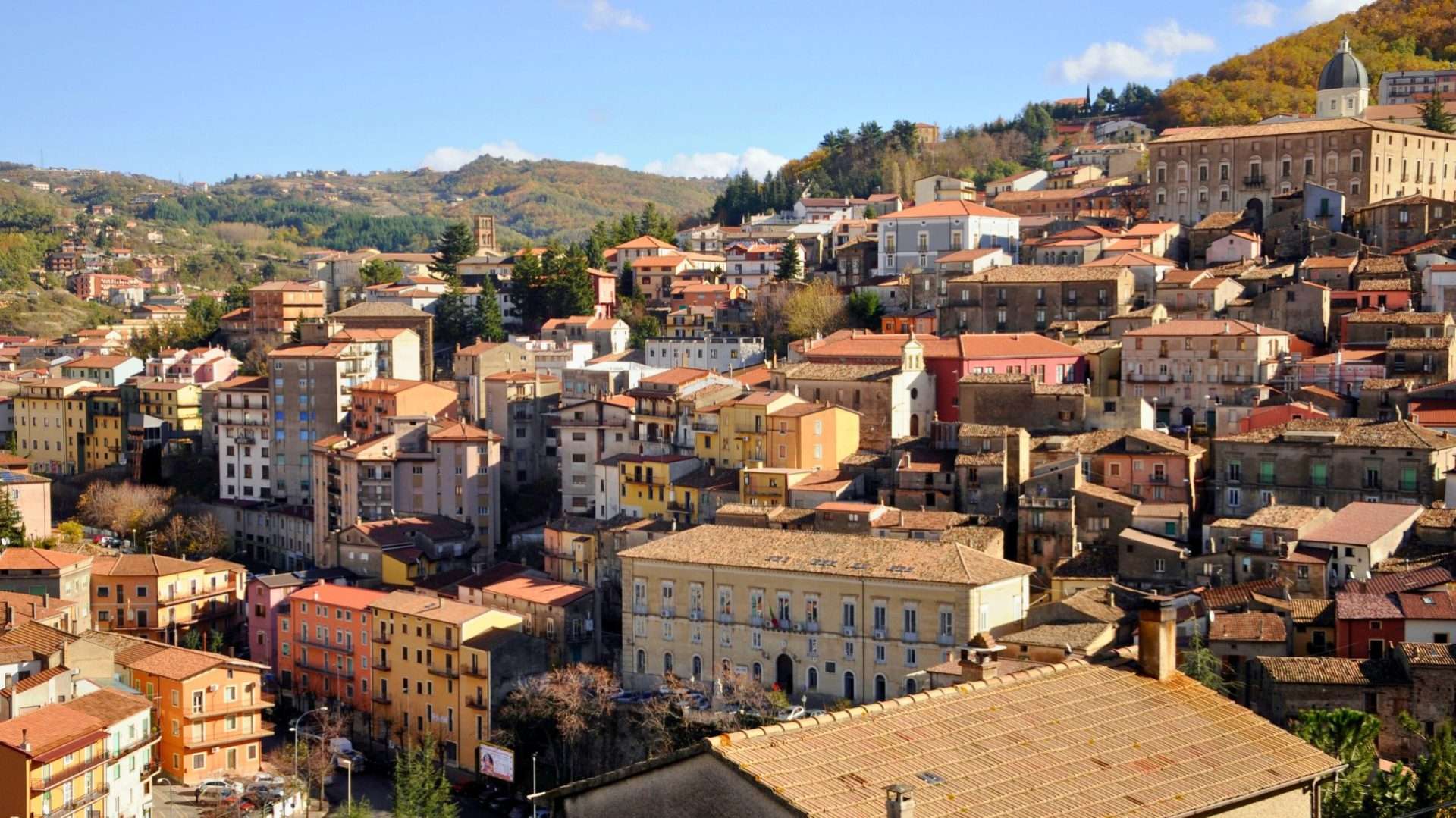 Casas de colores apiñadas del pueblo de montaña de Acri ante montes boscosos
