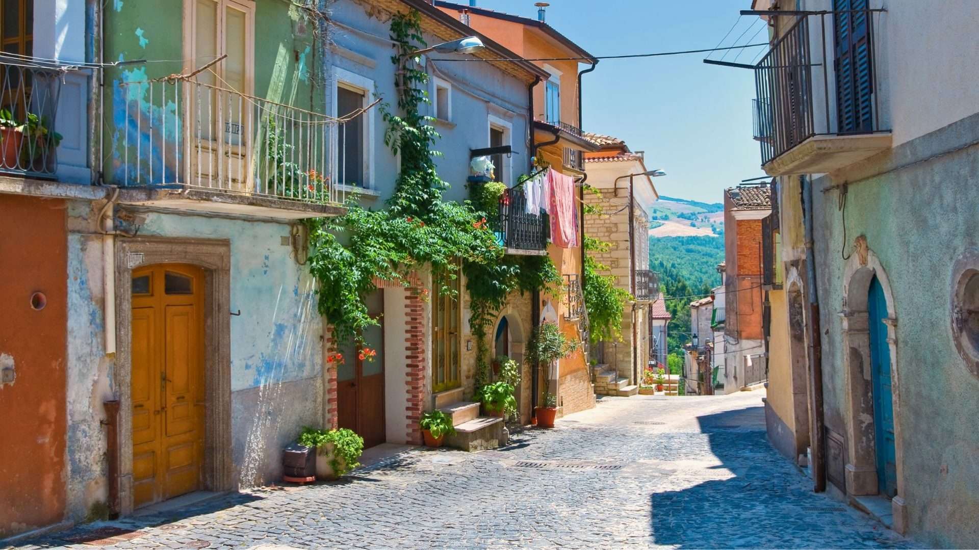 Callejón empedrado con casas de piedra, puertas de madera y enredaderas en Roseto Valfortore