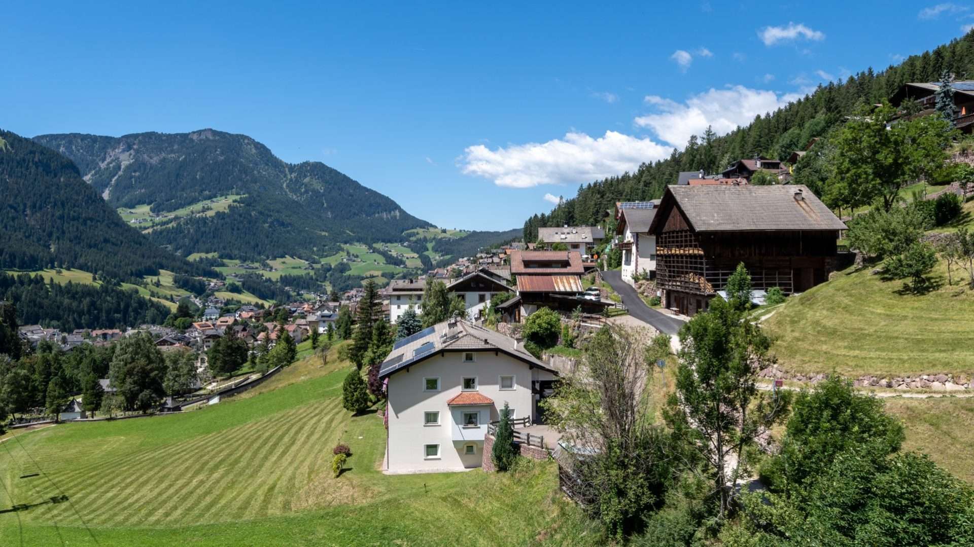 Pueblo alpino con casas de madera y prados frente a montañas boscosas en Trentino